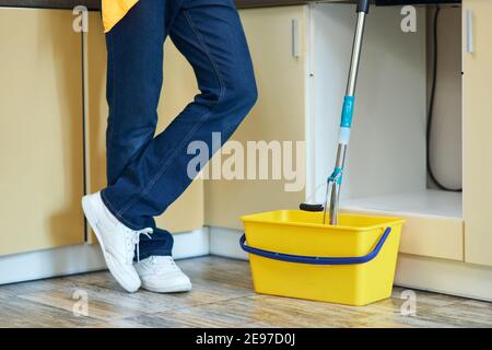 Richtig gereinigt. Kurzer Schuss professioneller männlicher Reiniger, der neben dem Eimer mit Mopp steht und bereit ist, den Boden zu Hause zu reinigen Stockfoto