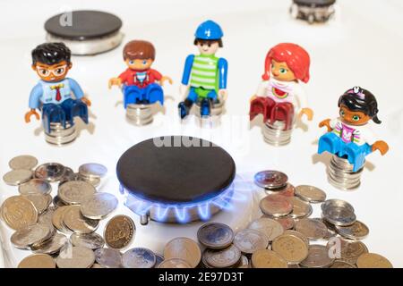 Die Leute sitzen in der Nähe des Gasbrenners auf dem Herd und Münzen des Geldes. Der Preis für Gas und Versorgungsunternehmen in der Welt. Stockfoto