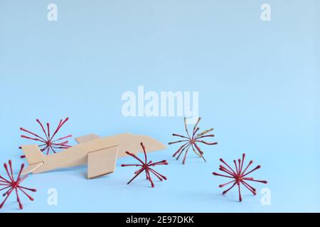 Geparktes hölzernes Flugzeugmodell auf himmelblauem Hintergrund mit Coronavirus. Reiseverbot und stornierter Urlaub aufgrund des covid-19-Pandemiekonzepts. Stockfoto