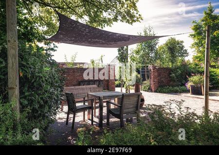 Appeltern, Niederlande, 30. Juli 2020: Trendiger Garten mit Terrasse und Überhang, dekoriert mit trendigen Gartenmöbeln und Pflanzgefäßen in einem Garten Stockfoto