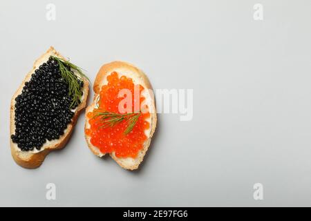 Sandwiches mit rotem und schwarzem Kaviar auf grauem Hintergrund, Platz für Text Stockfoto