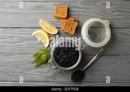 Glas mit schwarzem Kaviar, Brot, Dill und Zitrone auf Holzhintergrund, Draufsicht Stockfoto