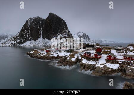 Landschaft der Lofoten-Inseln in Norwegen mit traditionellem Holz Rote Fischerhütten vor dem Meer und dies Schöne Moutain im Hintergrund Stockfoto
