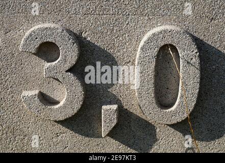 '3,0' auf einer grauen deutschen Mauer. Das Komma wird in Europa verwendet, um den Dezimalpunkt anzuzeigen. Stockfoto