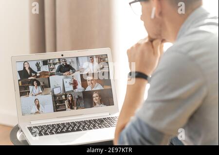 Brainstorming, Online-Videotreffen, virtuelle Konferenz mit Kollegen aus verschiedenen ethnischen Gruppen, Mitarbeitern und Kollegen. Blick über die Schulter eines Mannes auf einem Bildschirm mit Stockfoto