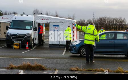 Ein NHS Test and Trace Arbeiter leitet ein Auto bei einer Fahrt durch Testzentrum in Southport, Lancashire. Ein Testblitz von 80.000 Menschen in England zielt darauf ab, "jeden einzelnen Fall" der südafrikanischen Coronavirus-Variante zu finden, um die Ausbreitung des ansteckenden Stammes zu stoppen. Bilddatum: Mittwoch, 3. Februar 2021. Stockfoto