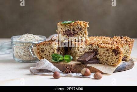 Haferflocken Quadrate mit Schokolade, Nüsse, Stücke von Schokolade und Minze, hellen Beton Hintergrund. Diät-Bars. Gesunde Bäckerei zum Frühstück oder Dessert. Sel Stockfoto