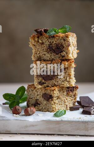 Haferflocken Quadrate mit Schokolade, Nüsse, Stücke von Schokolade und Minze, hellen Beton Hintergrund. Diät-Bars. Gesunde Bäckerei zum Frühstück oder Dessert. Sel Stockfoto