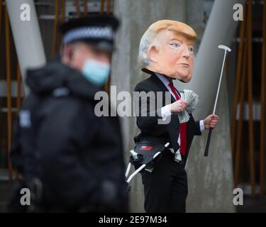 Edinburgh, Schottland, Großbritannien. 3. Februar 2021. Im Bild: Vor einer Debatte und einer Abstimmung im schottischen Parlament, um zu entscheiden, ob die schottische Regierung Donald Trumps Finanzierung schottischer Golfplätze untersuchen sollte, werden Aktivisten einen gefälschten Trump darstellen, der einen riesigen Kopf, eine rote Krawatte und ein Schild mit der Aufschrift „Investigate Me!“ trägt. Vor dem schottischen Parlament. Er wird auch schleppen seine Golftasche überfüllt mit Dollarnoten. Quelle: Colin Fisher/Alamy Live News Stockfoto