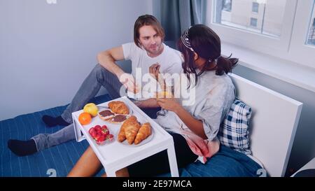 Junges multirassisches Paar mit Frühstück im Bett. Hochwertige Fotos Stockfoto
