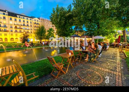 Genf, Schweiz - 14. Aug 2020: Leute trinken draußen Aperitif im Cottage Cafe rund um die Brunnen im Jardin des Alpes in Genf, Französisch-Schweizer Stockfoto