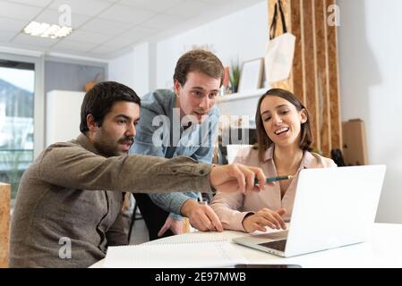Drei Kollegen diskutieren und schauen auf einen Laptop. Stockfoto