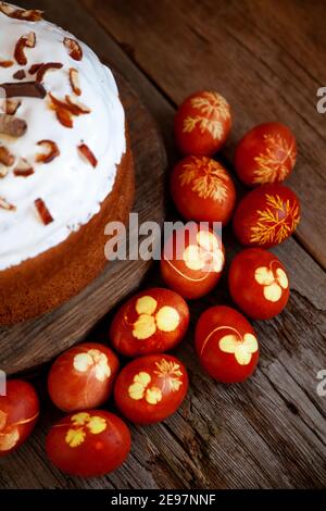 Osterkuchen und bunte Eier. Rustikales Essen auf einem Holztisch. Traditionelles Ei mit Zwiebelschale gefärbt. Muster aus Kleeblättern und Dillblättern. Klassisches Essen für Stockfoto