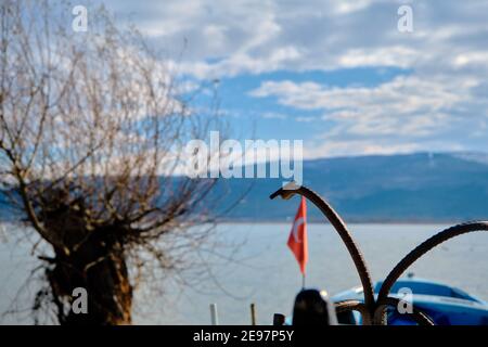 Anker auf den kleinen und blauen Booten mit See von uluabat und riesigen Berg Hintergrund. Türkische Flaggen auf den Booten in der Nähe des alten und getrockneten Baumes. Stockfoto