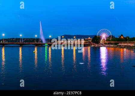 Das Schweizer Riesenrad und die Pont du Mont-Blanc spiegeln sich auf der Rhone mit Blick auf den See Leman, Französisch Schweizer. Nacht Blick auf Jet d'Eau Brunnen und Stockfoto