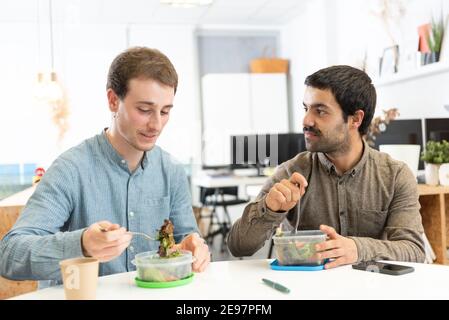 Gesunde Ernährung am Arbeitsplatz Konzept. Zwei Kollegen beim Mittagessen im Büro. Stockfoto