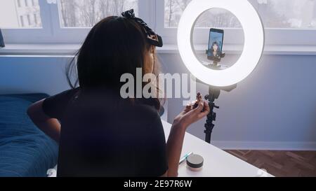 Junge Frau mit schwarzen Haaren Aufnahme Make-up Tutorial. Make-up vor der Kamera auftragen. Hochwertige Fotos Stockfoto