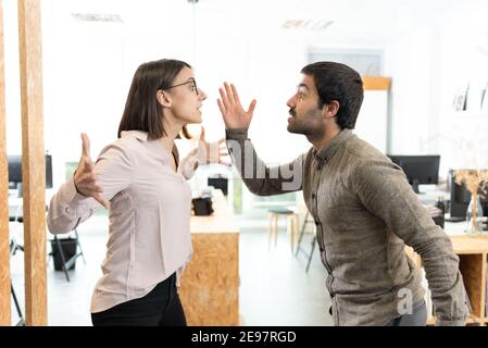 Zornige hispanische Kollegen diskutieren und streiten im Büro. Stockfoto
