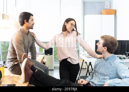 Drei verschiedene junge Kollegen plaudern entspannt im Büro. Stockfoto