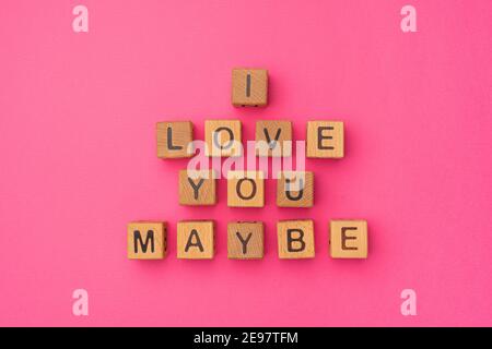 Holzwürfel mit der Phrase I Love You vielleicht auf einem leeren bunten rosa Hintergrund. Worte der Liebe sind aus Briefen aus Holz für Ihre Freundin, Freund, Frau, Mann, für Valentinstag Gruß romantische Postkarte. Flach liegend, Draufsicht Stockfoto