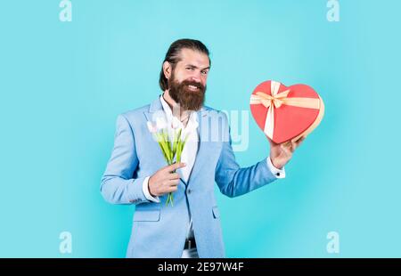 Zeit zum Einkaufen. Liebesgeschenk für romantische Datum. Bärtiger Mann in eleganter Jacke halten Blumen. Hochzeitstag. Happy valentines Tag. Braut Bräutigam mit Blumenstrauß und Box. Hipster Mann halten Tulpenblumen. Stockfoto