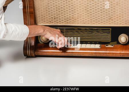 Beschnittene Ansicht der Frau, die Taste auf Vintage-Radio-Receiver drückt Auf Grau Stockfoto