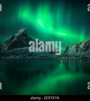 Nordlichter über den Lofoten in Norwegen. Der Sternenhimmel im Winter. Blick auf die Berge und Hamnoy vom Hafen reine. Stockfoto