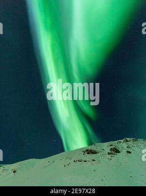 Grüne Lichter der Nordlichter über verschneiten Gipfeln der Lofoten Inseln. Winternacht in Nordnorwegen. Stockfoto