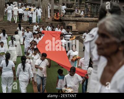 ANURADHAPURA, SRI LANKA - 9. März 2019: Pilger tragen endlos lange neue orange Tuch angeboten werden Stockfoto