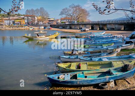Viele bunte Boote und Kanus an der Küste des Lake Uluabat und Parkplatz von Autos in der Nähe des Sees. Bursa. Golyazi. Türkei. 22,01.2021. Stockfoto