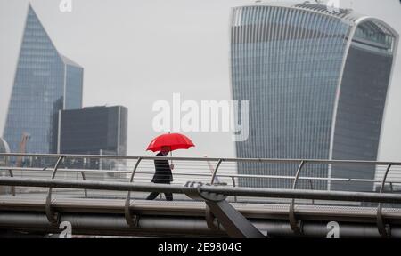 Ein Mann unterzieht sich unter einem Schirm, als er eine nahe verlassene Millennium Bridge im Zentrum Londons überquert, während Englands dritter nationaler Abriegelung, um die Ausbreitung des Coronavirus einzudämmen. Bilddatum: Mittwoch, 3. Februar 2021. Stockfoto