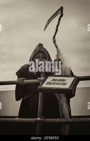 Immer ein Töten dieser Zeit des Jahres, grimmig reaper schwingende Sense nimmt an Weymouth Karneval in Weymouth, Dorset UK im August Stockfoto