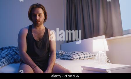 Junger Kaukasier sitzt auf dem Bett. Schlaflosigkeit Problem, psychische Störung oder Depression. Hochwertige Fotos Stockfoto