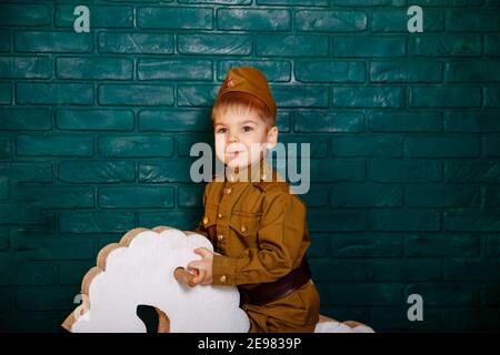 Kind reitet weißes Pferd. Kind in einem Anzug. Kinder spielen mit Spielzeug. Stockfoto