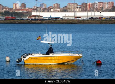 Kleines gelbes Motorboot mit Außenbordmotor, das an einer roten Boje in der Bucht von Santander Cantabria in Spanien festgemacht ist Stockfoto