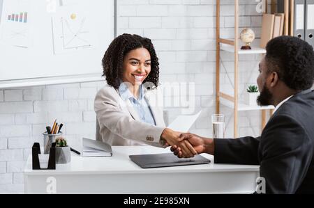 Positive weibliche Personalmanagerin und schwarze Jobbewerberin schüttelt die Hände Vor Arbeitsgespräch im Büro des Unternehmens Stockfoto