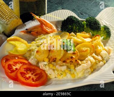 Kabeljau und Garnelen backen auf einem weißen Fischteller mit Gemüse Stockfoto