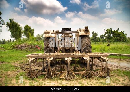 Traktor steht in Paddy Farm Land. Landwirtschaftliche Landschaftansicht in Indien mit Traktor im Vordergrund. Stockfoto