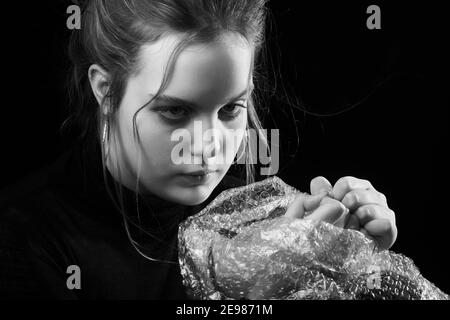 Gestresste Frau in Depression platzt Blasen der Verpackung Cellophan monochrom Stockfoto