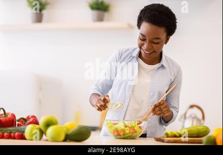 Happy Black Woman Kochen Gesunde Gemüse Salat Steht In Der Küche Stockfoto