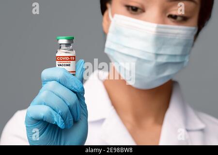 Schwarz Weibliche Arzt In Schützende Medica Maske Halten Fläschchen Mit Covid-19-Impfstoff Stockfoto