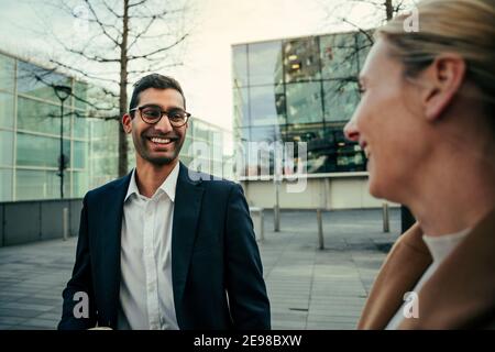Gemischtes Rennen männlich lächelnd plaudern zu schönen kaukasischen weiblich zu Fuß Gemeinsam arbeiten Stockfoto