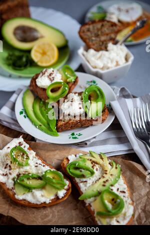 Sandwiches mit Weichkäse, Avocado und Gurke. Frühstück ist auf dem Tisch. Gesunde Ernährung. Toasten und darauf verteilen. Avocado Sandwich Stillleben. Gesundheit Stockfoto