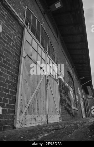 Die Verladerampe eines alten Lagerhauses, Verladerampe und ein Schiebetor eines alten Lagerhauses, schwarz-weiß Foto Stockfoto