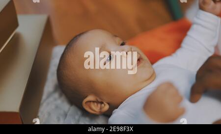 Liebenswert Baby hält Vater Hand. Mulatto Baby spielt mit väterlichen Hand. Nahaufnahme. Hochwertige Fotos Stockfoto