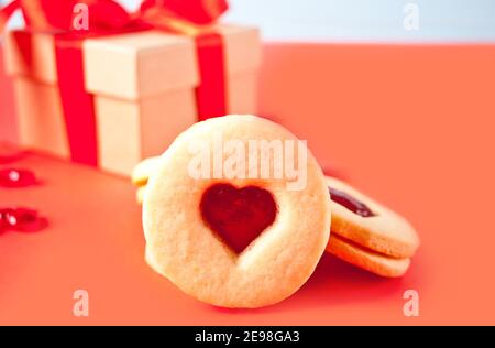 Herzförmige traditionelle linzer Kekse mit Erdbeermarmelade mit Geschenkbox auf dem Hintergrund. Valentinstag-Konzept Stockfoto