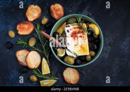 Gebackener Feta-Käse mit Zitrone, Oliven und Rosmarin. Stockfoto