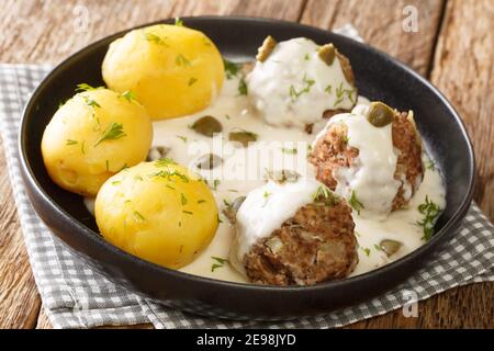 Leckere deutsche Konigsberger Klopse Fleischbällchen in Kapersoße serviert mit gekochten Kartoffeln close-up in einem Teller auf dem Tisch. Horizontal Stockfoto