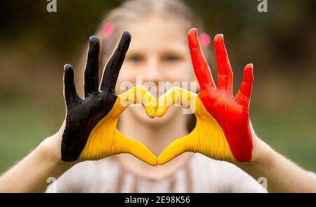 Kinder Hände in Belgien Flagge Farbe gemalt zeigen Symbol des Herzens und Liebe Geste auf Natur Hintergrund. Konzentrieren Sie sich auf die Hände Stockfoto