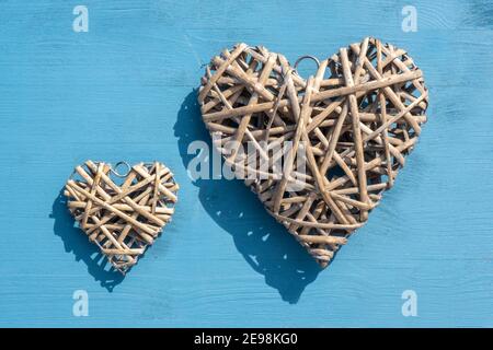 Feier- und Special Event-Konzept: Draufsicht auf zwei separate, hölzerne Herzkranz. Entfernung kleines und großes Symbol. Hintergrund in Holzblau. Stockfoto